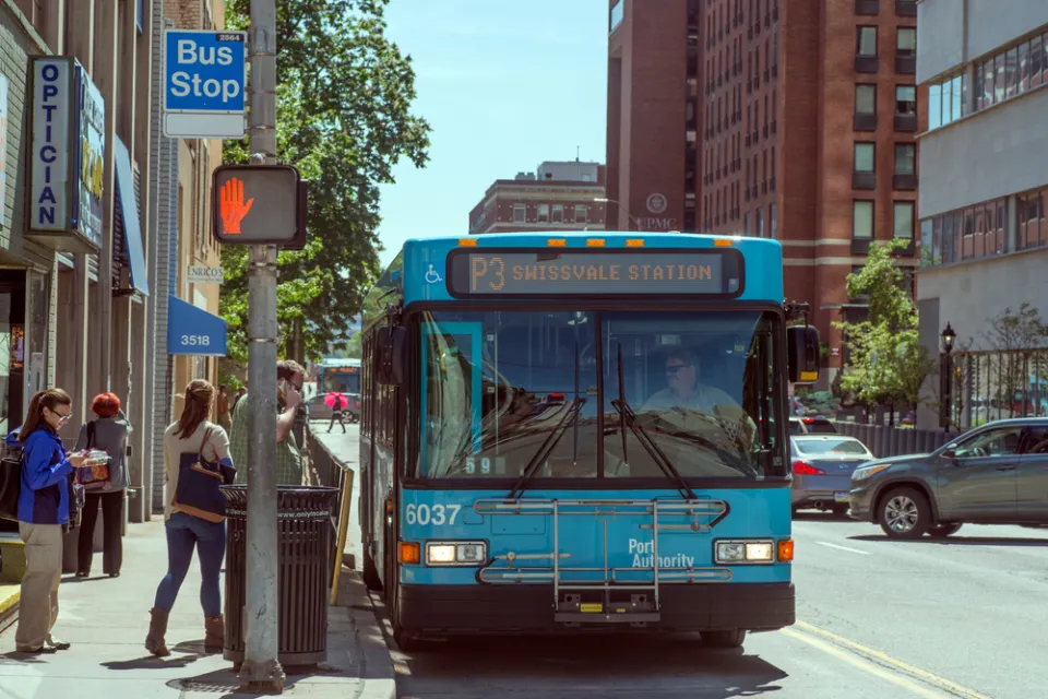 Bus stop in Pittsburgh, Pennsylvania with blue bus and passengers boarding